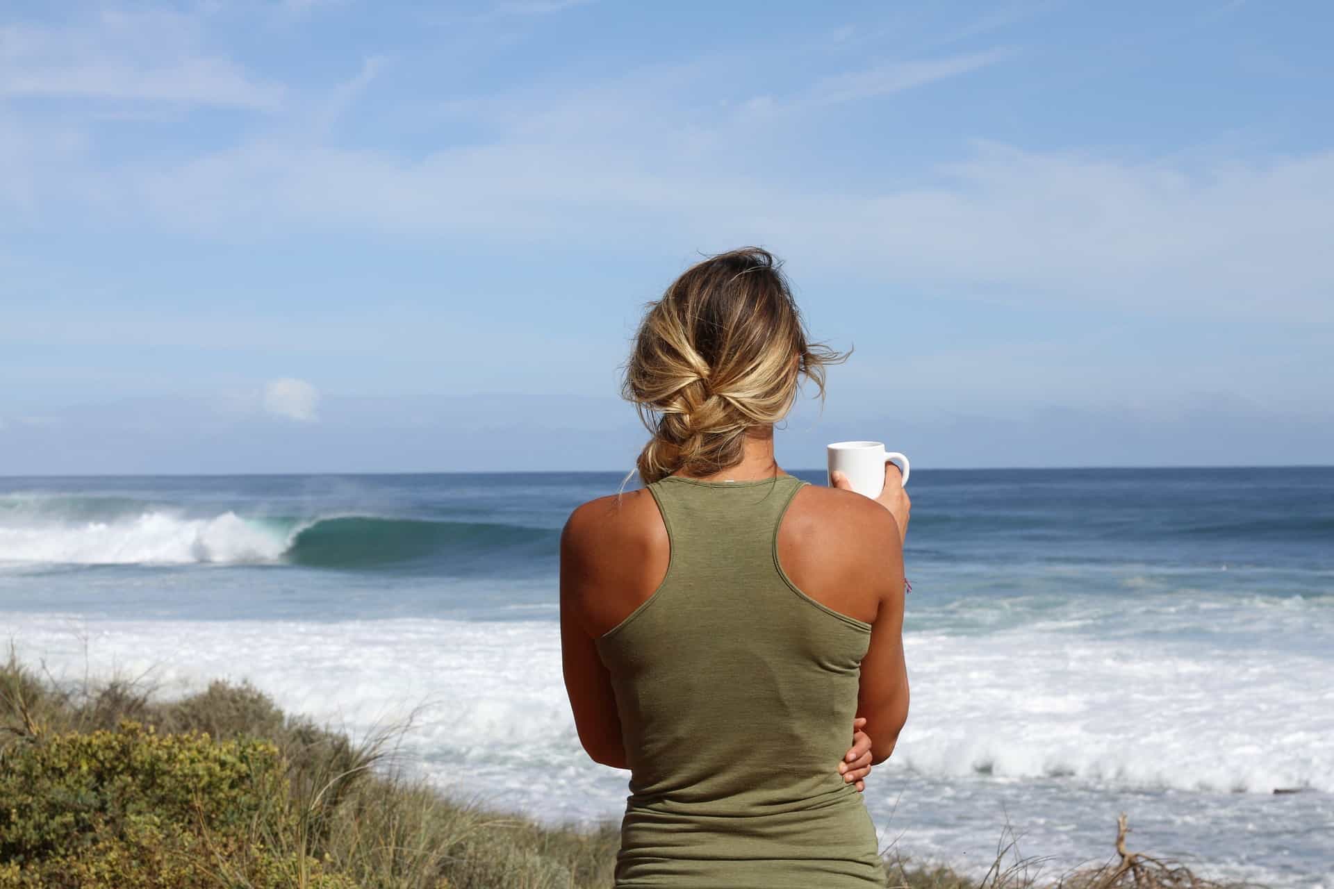 Frau am Strand mit Teetasse